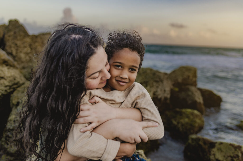 mom hugging son on beach