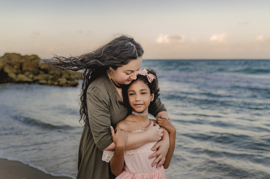 mom hugging daughter on beach